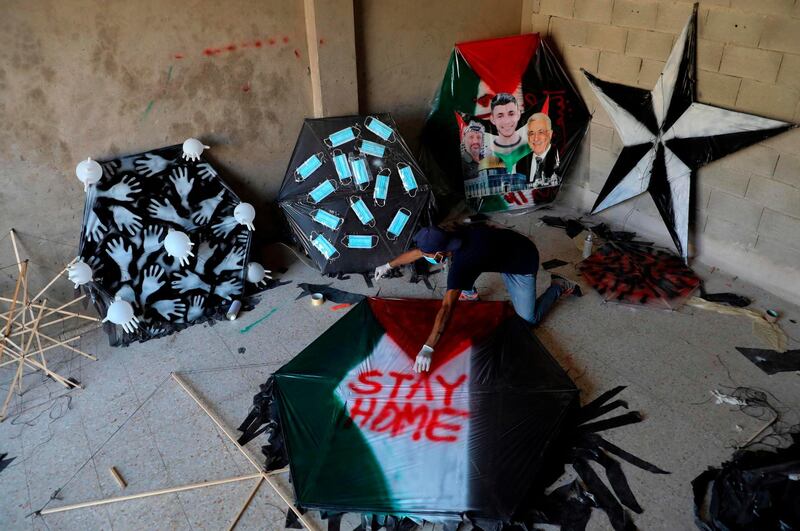 Ibrahim, a 29-year-old Palestinian, makes a kite with a safety message regarding the coronavirus pandemic in the village of Halhoul, north the West Bank town of Hebron.   AFP