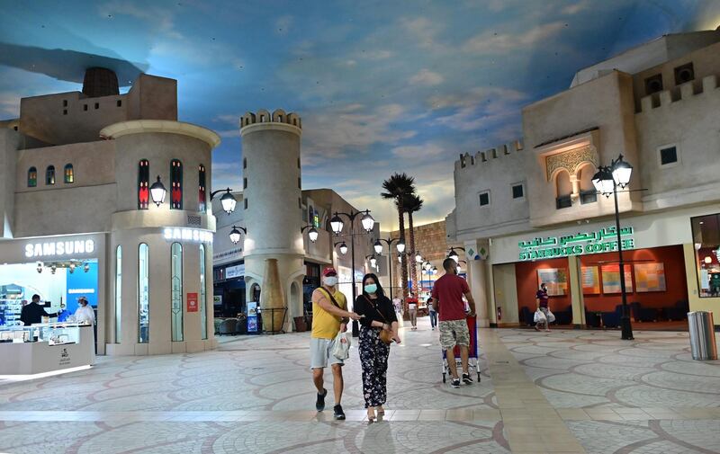 People, wearing protective masks to prevent the spread of the coronavirus, walk in Ibn Battuta mall in Dubai.  AFP
