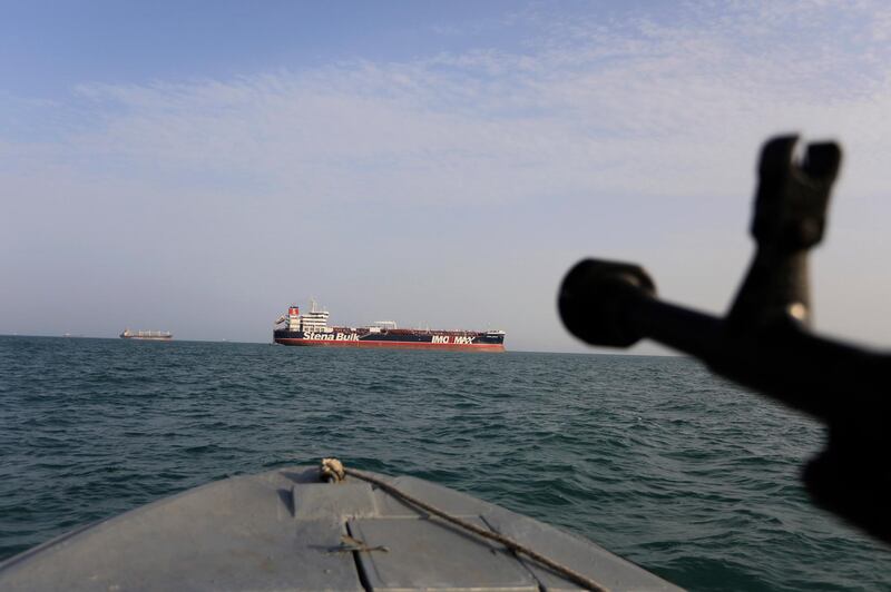 FILE - In this In this July 21, 2019 file photo, a speedboat of Iran's Revolutionary Guard trains a weapon toward the British-flagged oil tanker Stena Impero, which was seized in the Strait of Hormuz on July 19 by the Guard, in the Iranian port of Bandar Abbas. Iranian forces seized a ship in the Persian Gulf suspected of carrying smuggled fuel, state media reported Sunday, Aug. 4, 2019, marking the Revolutionary Guard's third seizure of a vessel in recent weeks and the latest show of strength by the paramilitary force amid a spike in regional tensions. State TV and the semi-official Fars news agency reported that seven crew members were detained when the latest ship was seized late Wednesday. (Morteza Akhoondi/Tasnim News Agency via AP, File)