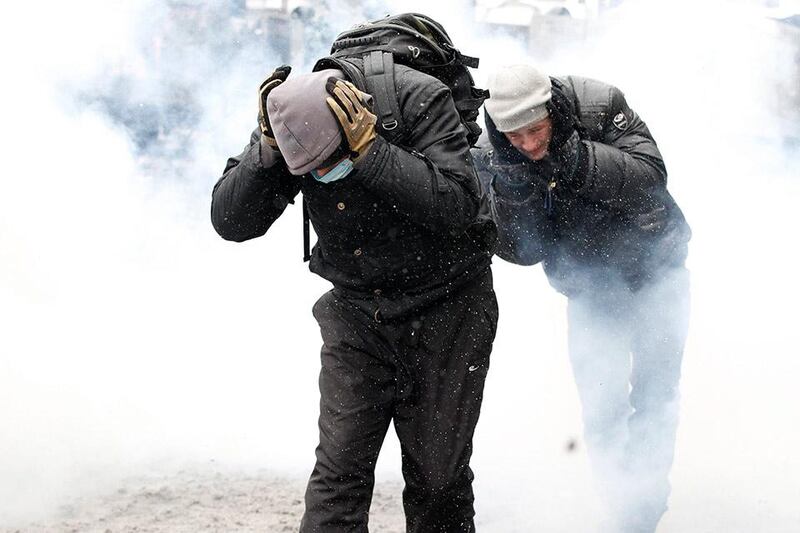 Pro-European protesters cover their ears while running amidst smoke during clashes with riot police in Kiev January 22, 2014. Ukrainian President Viktor Yanukovich has agreed to meet the three main opposition leaders on Wednesday for talks on a crisis that has led to violent clashes between protesters and police, said one of the leaders, Arseny Yatsenyuk. REUTERS/Vasily Fedosenko (UKRAINE - Tags: POLITICS CIVIL UNREST)