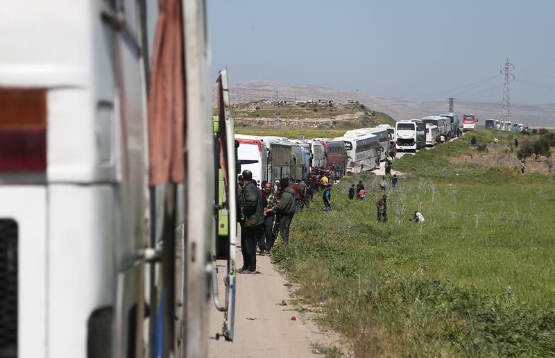 A convoy transporting Syrian civilians and rebel fighters evacuated from Eastern Ghouta waits in a government-held area prior to entering the village of Qalaat al-Madiq, some 45 kilometres northwest of the central city of Hama, on March 26, 2018, as evacuations from the opposition enclave continued following a deal that was announced earlier in the week. Abdulmonam Eassa / AFP