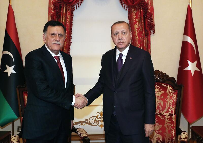A handout picture taken and released on December 15 , 2019 by the Turkish Presidential Press service shows Turkey's President Recep Tayyip Erdogan (R), shakeing hands with Fayez al Sarraf (L), the head of the Tripoli-based Government of National Accord (GNA) during their meeting in Istanbul. / AFP / TURKISH PRESIDENTIAL PRESS SERVICE / Murat CETINMUHURDAR

