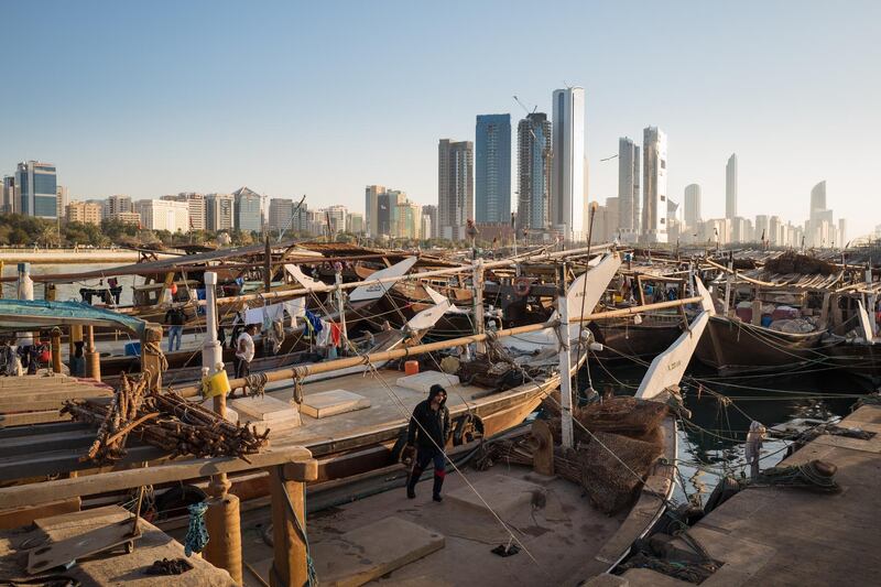 A harbour worker crosses Arab dhows in Mina Zayed. About 130 dhows are moored at the harbor. Courtesy Sohail Karmani