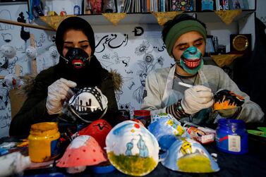 Palestinian artists Samah Said (L) and Dorgham Krakeh (R) paint N95 protective masks for a project raising awareness about the COVID-19 coronavirus pandemic, in Gaza City on March 24, 2020. / AFP / MOHAMMED ABED