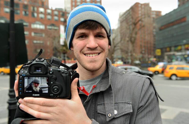 Brandon Stanton (L), creator of the Humans of New York blog, shows an image he took of a man named Carl February 22, 2013 across the street from Union Square in New York. Some like New York's skyscrapers, bridges, his energy, taxis or lights. But Brandon Stanton has set himself another challenge: photograph of 10,000 inhabitants for a blog now famous "Humans of New York."  In two years, he has photographed 5,000 New Yorkers, children leaving school, tramps, fashionistas, New York with a bouquet of tulips, old lady with a cane, municipal employees, etc. And nearly 560,000 fans now follow his Facebook page.AFP PHOTO/Stan HONDA / AFP PHOTO / STAN HONDA
