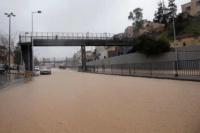 People cross a pedestrian bridge over a flooded street during heavy rains in Amman, Jordan. Reuters