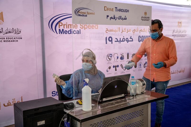 A health worker wearing protective gear prepares to take swab samples from people queuing in their cars. AP Photo