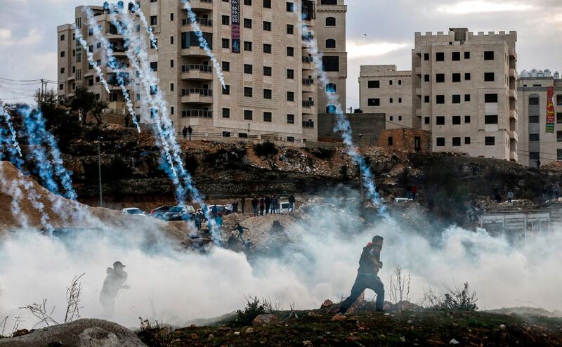 TOPSHOT - Palestinian protesters run from falling tear gas canisters fired by Israeli forces during clashes near an Israeli checkpoint in the West Bank city of Ramallah on December 10, 2017, following the US president's controversial recognition of Jerusalem as Israel's capital.
New protests flared in the Middle East and elsewhere over US President Donald Trump's December 6 declaration of Jerusalem as Israel's capital, a move that has drawn global condemnation and sparked days of unrest in the Palestinian territories. / AFP PHOTO / ABBAS MOMANI