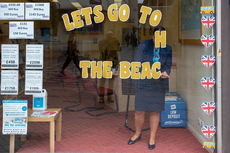 A woman changes a window display in a travel agency in Wakefield town centre. Getty Images