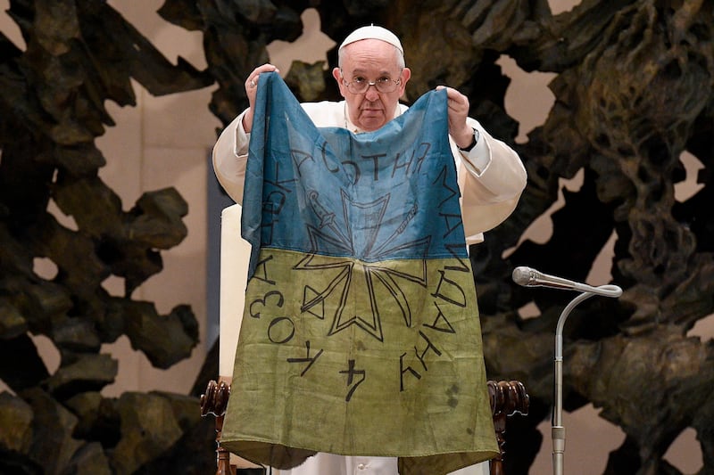 Pope Francis holds a Ukraine flag sent to him from the Ukrainian town of Bucha during the weekly general audience in the Paul VI Audience Hall, Vatican City, on April 6. EPA 