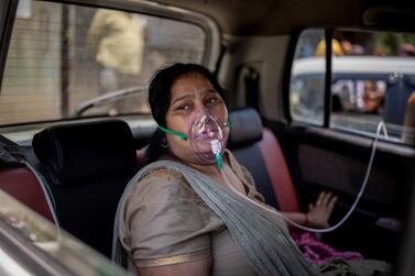 A COVID-19 patient sits in a car and breathes with the help of oxygen in New Delhi, India. AP