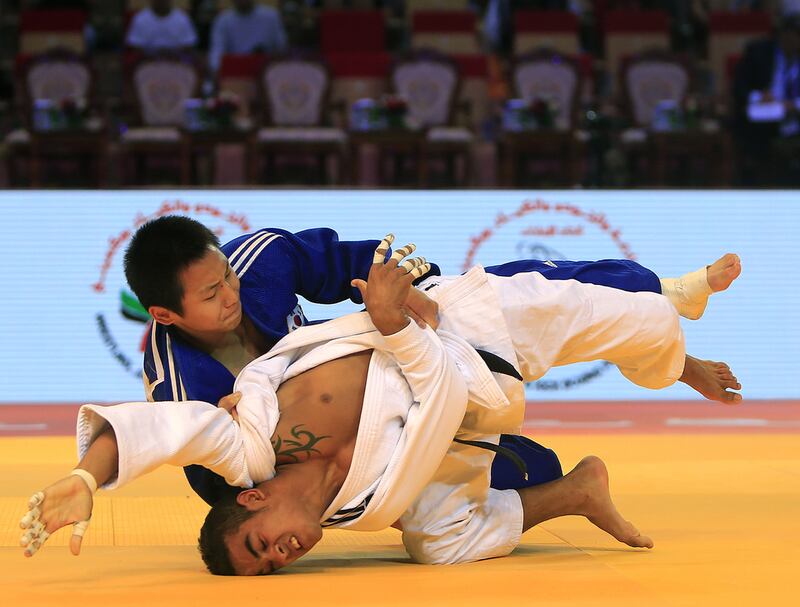 Channyeong Kim, in blue from South Korea, fights with Yandey Torres Marimon from Cuba on the opening day of the International Judo Federation (IJF) Junior World Championships, which started at the Ipic Arena at the Zayed Sports City in Abu Dhabi on Friday. Ravindranath K / The National