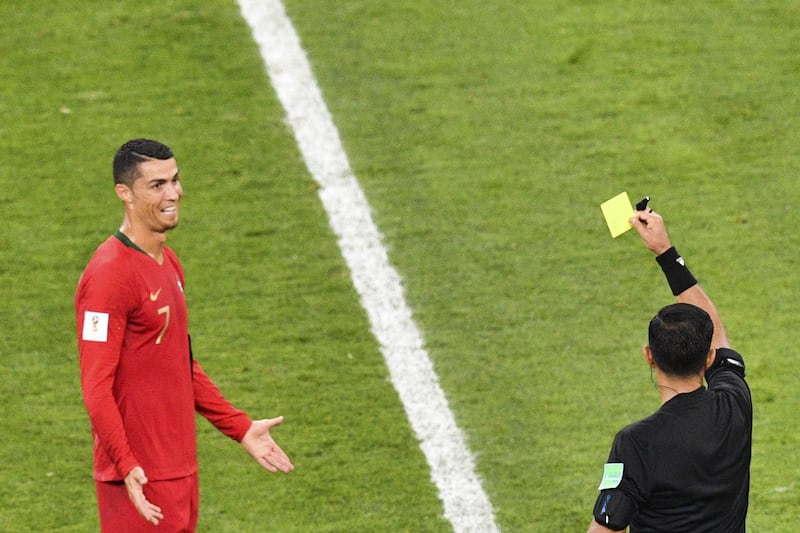 Paraguayan referee Enrique Caceres shows the yellow card to Portugal's forward Cristiano Ronaldo during the Russia 2018 World Cup Group B football match between Iran and Portugal at the Mordovia Arena in Saransk on June 25, 2018. (Photo by Mladen ANTONOV / AFP) / RESTRICTED TO EDITORIAL USE - NO MOBILE PUSH ALERTS/DOWNLOADS