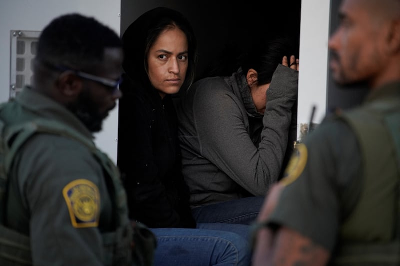 Women wait after being apprehended crossing the US - Mexico border in Sunland Park, New Mexico. Reuters