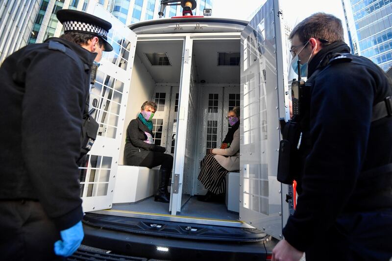 Activists from the Extinction Rebellion, a global environmental movement, sit inside a police car after being detained outside the Barclays offices, in Canary Wharf, London, Britain, April 7, 2021. REUTERS/Toby Melville