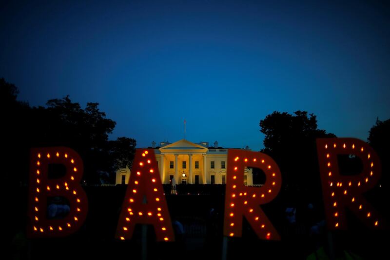 Protesters hold signs which read 'Barr', following the release of the Mueller report,  at the White House in Washington. Reuters