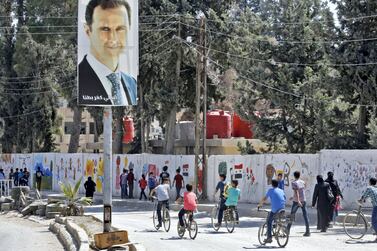 A poster of Syrian President Bashar Al Assad looks down on students going to school in the recaptured rebel-held area of Eastern Ghouta in September 2018. AFP