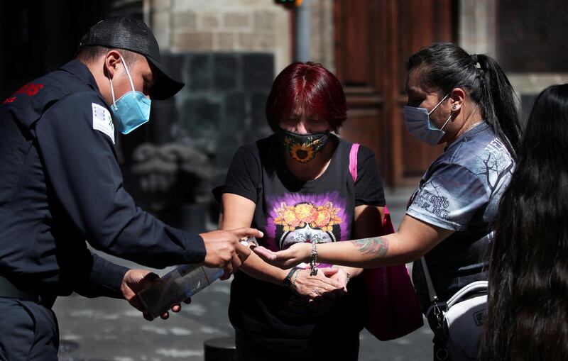 A firefighter gives disinfectant gel to women out shopping in Mexico City. AP Photo