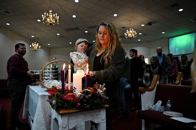 A woman holds her child as she lights a candle during a Christmas Eve service at Dawson Springs First Baptist church in, Kentucky, US. Getty