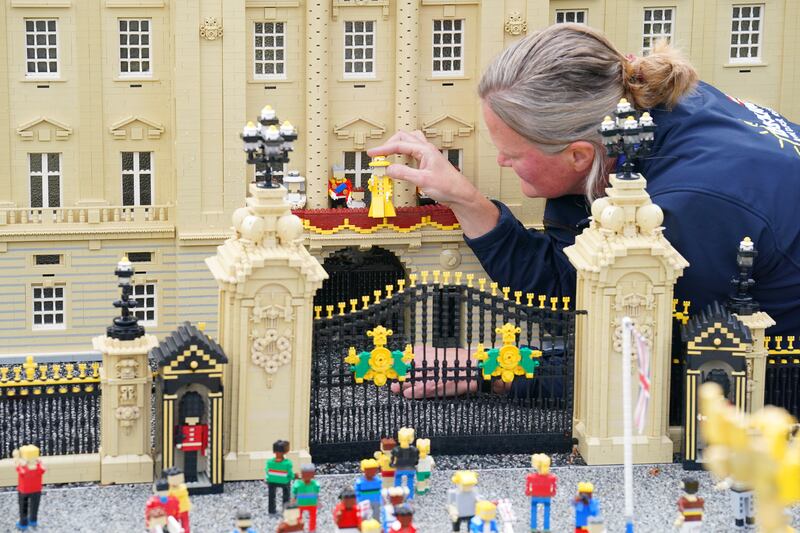 Model-maker Paula Young places a Lego replica of Queen Elizabeth II in a display replicating the royal balcony scene at Buckingham Palace for the Legoland platinum jubilee display in Windsor. PA