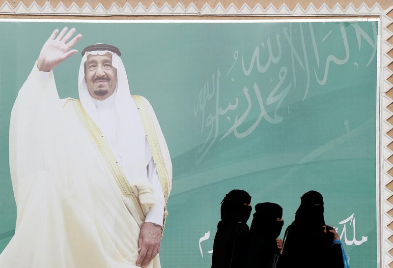 Women walk past a poster of Saudi Arabia's King Salman bin Abdulaziz Al Saud during Janadriyah Cultural Festival on the outskirts of Riyadh, Saudi Arabia February 12, 2018. Picture taken February 12, 2018. REUTERS/Faisal Al Nasser
