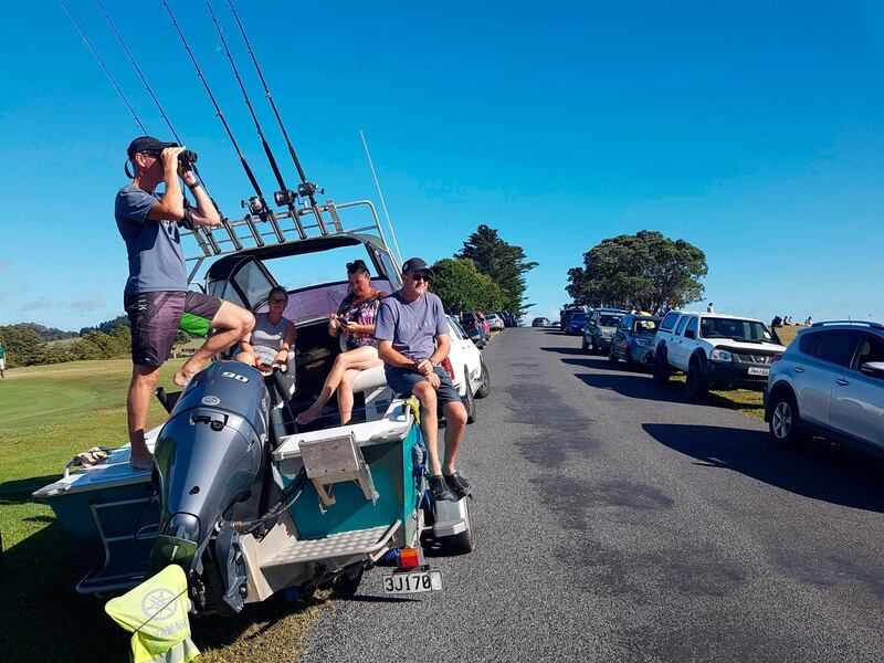 John Fitzgerald, left, on holidays with his wife Rita and friends, scans the horizon from high ground for any sign of a tsunami near Waitangi, New Zealand, Friday, March 5, 2021. A powerful magnitude 8.1 earthquake struck in the ocean off the coast of New Zealand prompting thousands of people to evacuate and triggering tsunami warnings across the South Pacific. (Peter De Graaf/New Zealand Herald via AP)