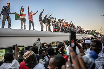 TOPSHOT - Sudanese protesters from the city of Atbara, flash the V-sign for victory and wave national flags atop a train, as it arrives at the Bahari station in Khartoum on April 23, 2019. The passengers, who had travelled from the town of Atbara where the first protest against ousted president Omar al-Bashir erupted on December 19, chanted "freedom, peace, justice". Many protesters perched on the roof of the train, waving Sudanese flags as it chugged through north Khartoum's Bahari railway station before winding its way to the protest site, an AFP photographer said. / AFP / OZAN KOSE
