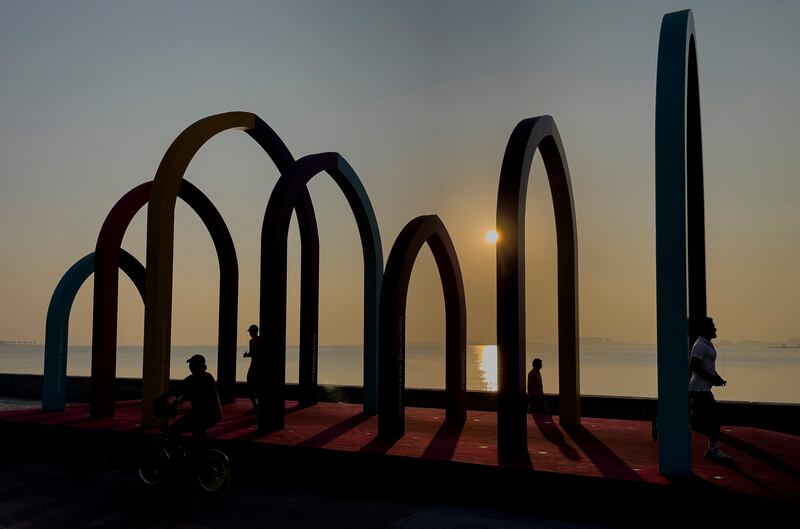 People walk under the colourful arches with the FIFA World Cup banner at the Doha Corniche, in Doha, Qatar.  The FIFA World Cup Qatar 2022 will take place from 20 November to 18 December 2022 in Qatar. EPA