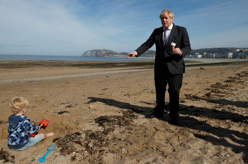 Britain's Prime Minister Boris Johnson holds an ice cream on the beach as he campaigns in Llandudno, north Wales, ahead of the May 6 Welsh elections. AFP