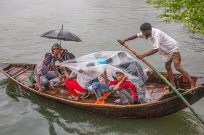 People cross the Buriganga river as they shelter themselves under plastic sheet during the rain and rough condition caused by cyclone Asani in Dhaka, Bangladesh, 10 May 2022.  According to the Bangladesh Meteorological Department (MET) office report, severe cyclone Asani is likely to weaken gradually into a cyclonic storm in next 12 hours and move northwest direction of the Bay of Bengal and the storm is expected without making a landfall.   EPA / MONIRUL ALAM