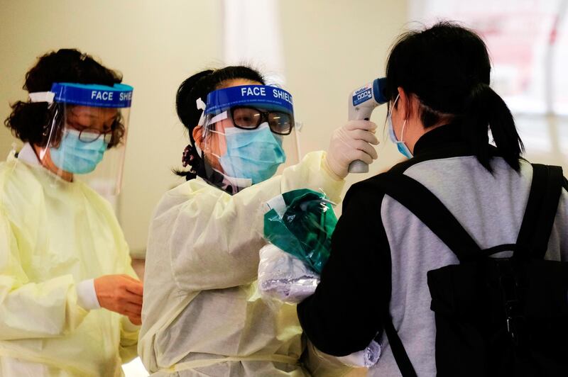 A medical worker takes the temperature of a woman in the reception of Queen Elizabeth Hospital, following the outbreak of the coronavirus, in Hong Kong, China. Reuters