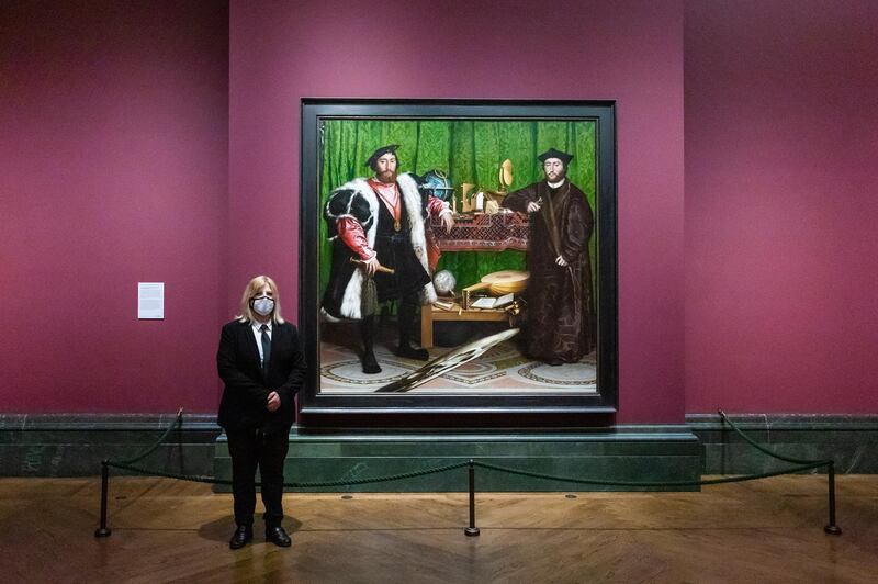 A member of staff wearing a face mask stands next to 'The Ambassadors' by Hans Holbein the Younger at the National Gallery, London. EPA