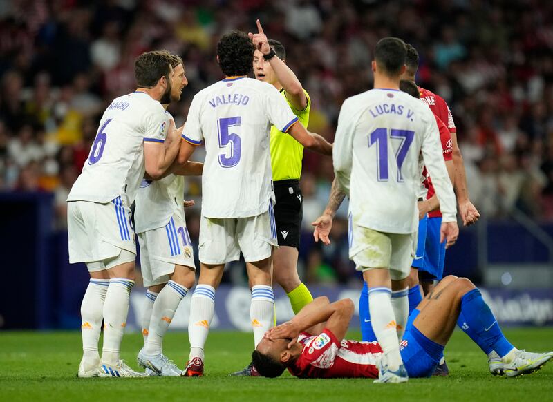 Atletico Madrid's Yannick Carrasco lies on the pitch in pain as Real Madrid players argue with referee Cesar Soto Grado. AP Photo