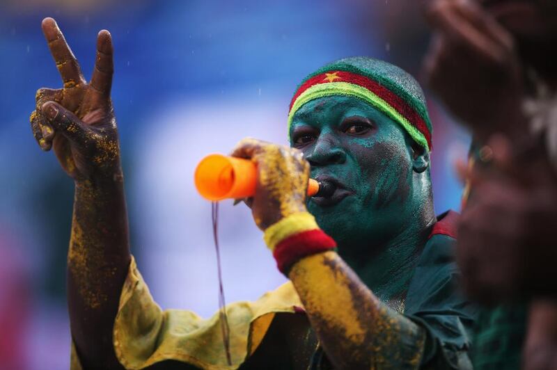A Cameroon fan blows a horn in the rain. Clive Rose / Getty Images