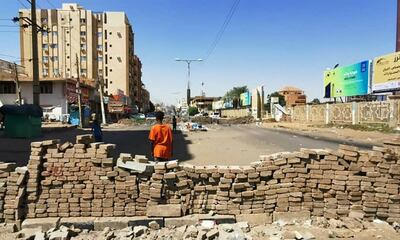 A young Sudanese man stands in front of a street barricade built overnight by anti-coup demonstrators in the capital Khartoum. 
AFP