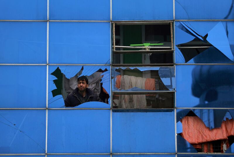 An Afghan man looks through a glass window damaged after a bombing attack in Kabul, Afghanistan. The strong car bomb explosion rocked the capital Kabul city on Sunday morning, killing multiple people, said a government official. AP Photo