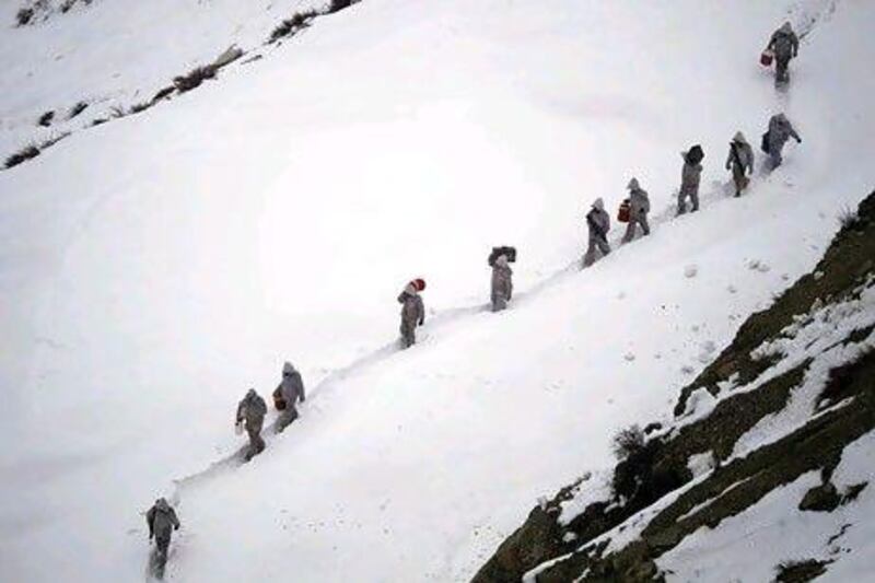 Pakistani army soldiers carry supplies up the 2,400 metre mountain near their outpost, Kalpani Base, in Pakistan's Dir district. Yesterday, an avalanche smashed into their base on a Himalayan glacier close to India.