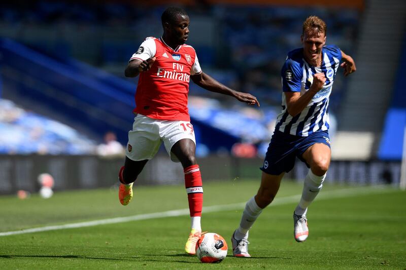 Arsenal's Nicolas Pepe, left, runs with the ball followed by Brighton's Dan Burn. AP