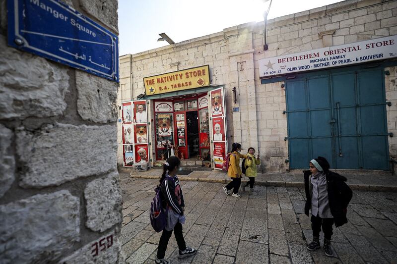 Children pass closed shops in Manger Square, Bethlehem, December 15, 2021. AFP