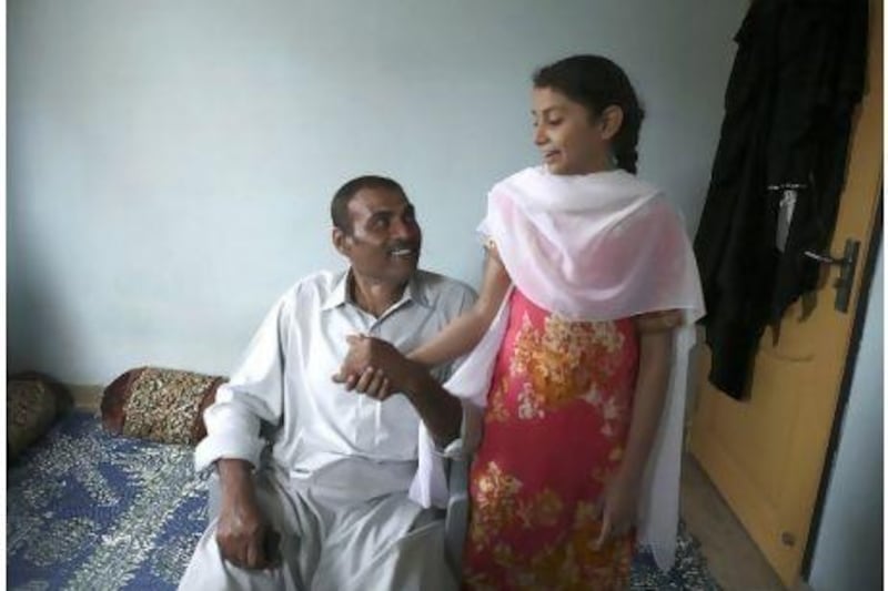 Crew member of MV Albedo, Faqir Muhammad Soomro, 48, sits with his 12-year-old daughter, Sidra, at his residence in Karachi, Pakistan. Asim Hafeez for The National
