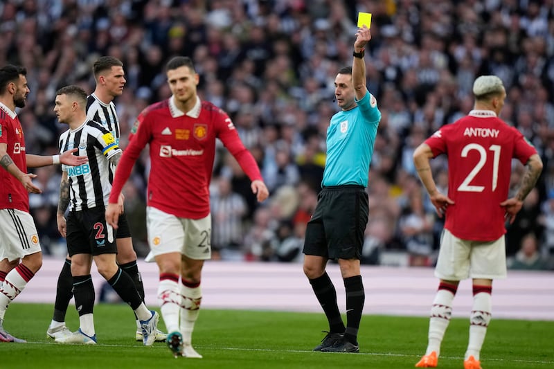 Referee David Coote shows a yellow card to Manchester United's Diogo Dalot. AP 