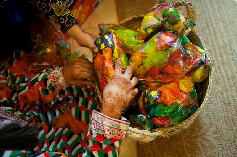 Sharjah, United Arab Emirates - June 23 2013 - Maitha Al Jabri, 4, and Hind Al-Suwaidi, 10, both cousins, pack little bags filled with sweets and crisps with at their home in the Leyyah district of the city. They are preparing for Hag El Leila, an Emirati tradition that occurs every year 15 days before the start of the month of Ramadan. The tradition involves children walking from door-to-door singing and collecting sweets and money. (Razan Alzayani / The National)  FOR RYM GHAZAL STORY  *** Local Caption ***  RA0623_hag_el_layla_002.jpg