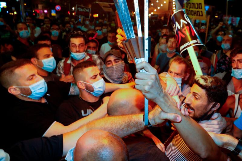 Protesters wearing protective face masks due to the COVID-19 coronavirus pandemic, clash with police during a demonstration on July 18, 2020, in Charles Clore Park in the Israeli coastal city of Tel Aviv to protest against the Israeli government and Prime Minister Benjamin Netanyahu for the broken promises made by the Israeli government during the Covid-19 pandemic. Israel's government said today it was imposing new restrictions to limit the spiraling spread of coronavirus in the hope of avoiding a general lockdown further along the line. / AFP / Jack GUEZ 
