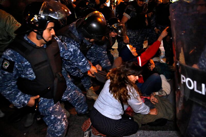Protesters lie on a road, as they scream and hold each others while riot police try to remove them and open the road, in Beirut. AP Photo