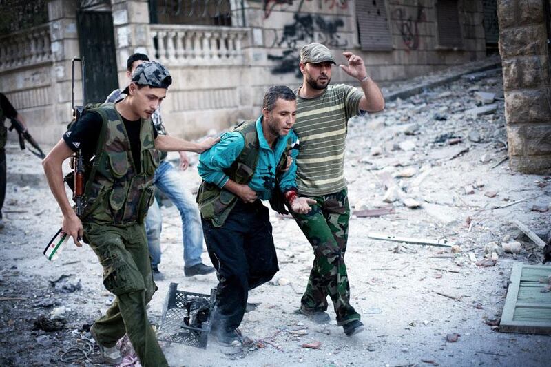 Rebel soldiers help a severely wounded fighter who was shot by a Syrian Army sniper in the Izaa district. Manu Brabo / AP Photo