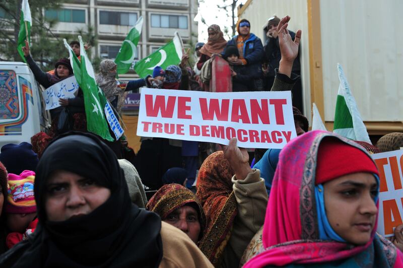 Pakistani supporters of Canadian-Pakistani cleric Tahir-ul Qadri  look on during a protest march in Islamabad on January 15, 2013. Police fired tear gas on protesters in Islamabad as clashes erupted with followers of a cleric who led a march on the city demanding a peaceful "revolution" and the dissolution of parliament. AFP PHOTO/ Farooq NAEEM
 *** Local Caption ***  259875-01-08.jpg