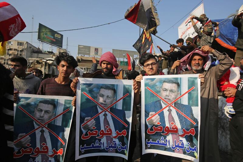 Iraqi anti-government protesters hold defaced posters of Assaad al-Aidani, the governor of Basra, reading in Arabic "rejected by the people" during a demonstration in Baghdad's Tahrir Square on December 26, 2019. Iraqi anti-government protesters blocked roads and bridges in Baghdad and the country's south after torching several buildings overnight. The demonstrators oppose the entire political class and have vented their anger against leaders who are negotiating to nominate an establishment insider as the next prime minister.
 / AFP / AHMAD AL-RUBAYE
