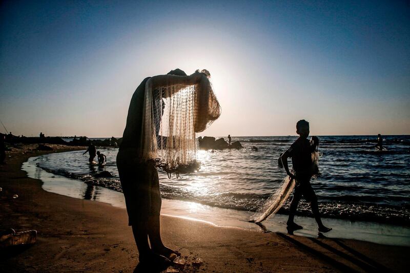A fisherman stands holding his nets by a beach off Gaza City near sunset.  AFP