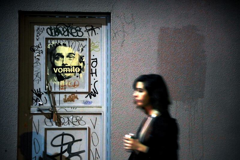 A woman walks in front of a poster displaying a message against far-right presidential candidate Jair Bolsonaro, in Sao Paulo, Brazil.  EPA
