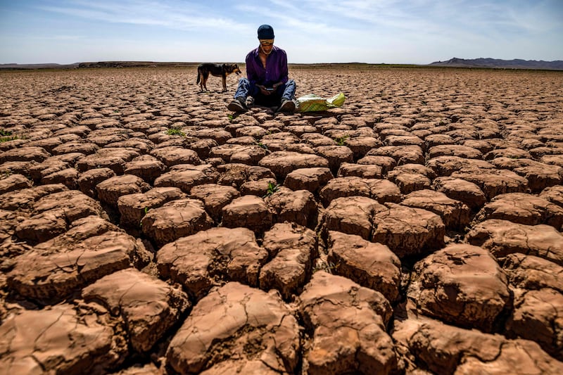 A shepherd on his mobile phone sits on cracked earth at Al Massira Dam in Ouled Essi Masseoud, about 140km south of Casablanca. AFP
